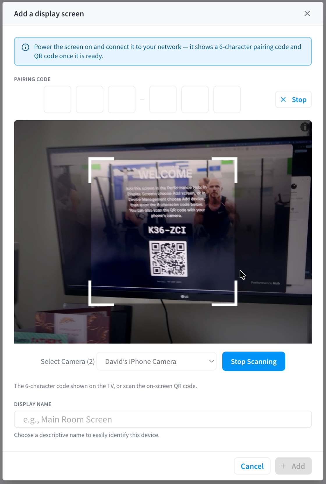 A phone scanning the QR code shown on the TV to pair the screen